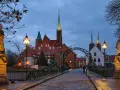 Most wrocławskiej katedry o zmierzchu z widokiem na wieże kościelne i rzeźby.
