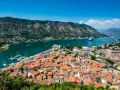 Widok na zabytkowe miasto Kotor w Czarnogórze z zatoką i górami w tle.