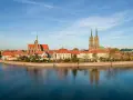 Widok na Ostrów Tumski we Wrocławiu z rzeką i odbiciem budynków w wodzie.
