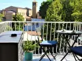 Balkon z widokiem na rzymskie budynki i zieleń, stolik z kawą.