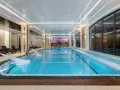Nowoczesny basen w hotelu spa z wodospadem i leżakami.