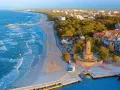 Widok z lotu ptaka na plażę, morze, latarnię morską i zabudowania Kołobrzegu.
