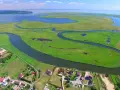 Krajobraz z lotu ptaka: zielone wyspy, meandrujące rzeki i zabudowania nad wodą.