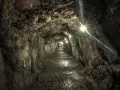 Wydrążony tunel skalny z oświetleniem, kamienista ścieżka.