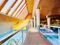 Wnętrze hotelowe z basenem, zjeżdżalnią i jacuzzi, drewniany sufit i ściany.