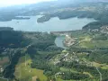 Widok z lotu ptaka na zalesione wzgórza, jezioro i zaporę wodną.