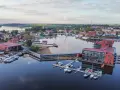 Widok na mazurskie miasteczko z nowoczesnym hotelem i mariną pełną łodzi.