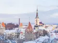Widok na zasypane śniegiem wieże i dachy Starego Miasta w Tallinnie.