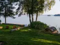 Taras z leżakami nad jeziorem, z widokiem na las i pomost.