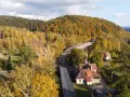 Widok z lotu ptaka na jesienne Góry Sowie z mostem kolejowym i domami.