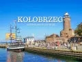 Port w Kołobrzegu z latarnią morską, statkiem pirackim i ludźmi na promenadzie.