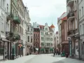 Ulica z kolorowymi kamienicami i ludźmi spacerującymi po bruku.