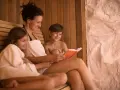 Kobieta czyta książkę dzieciom w saunie.