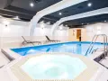 Wnętrze hotelowe z basenem, jacuzzi, sauną i leżakami.