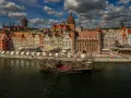 Żaglowiec na Motławie przed kolorowymi kamieniczkami w Gdańsku.