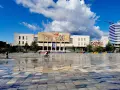 Plac w Tiranie z budynkiem Narodowego Muzeum Historii i kolorowymi pufami.