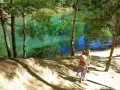 Dwie dziewczynki w słomkowych kapeluszach idą ścieżką nad turkusowym jeziorem.