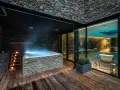 Nowoczesne jacuzzi z kamienną okładziną i oświetleniem, obok basenu.