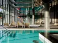 Basen z turkusową wodą i leżakami w nowoczesnym hotelowym spa.