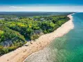 Widok z lotu ptaka na piaszczystą plażę w Jastrzębiej Górze z klifem i lasem.