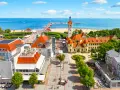 Widok z lotu ptaka na nadmorską miejscowość z plażą, molo i zabytkowymi budynkami.