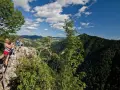 Widok z góry na turystów na skale, las i góry w tle.