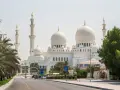 Wielki Meczet Szejka Zajida w Abu Zabi z minaretami i kopułami, otoczony palmami.