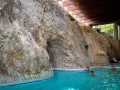 Basen w jaskini z wodospadem i ludźmi kąpiącymi się.
