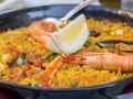 Paella z owocami morza i cytryną w czarnej patelni.