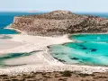 Widok na zatokę Balos na Krecie z turkusową wodą, piaszczystą plażą i skalistą górą.