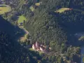 Widok z lotu ptaka na Czerwony Klasztor otoczony zielonymi wzgórzami i lasami.