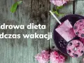 Lody jagodowe na patyku i w kształcie krążków na talerzu, ozdobione kwiatami.