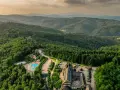 Widok z lotu ptaka na hotel SPA z basenem i zjeżdżalnią, otoczony lasem i górami.
