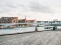 Nowoczesny most nad kanałem w Kopenhadze z ceglanymi budynkami w tle.