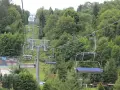 Kolejka krzesełkowa wznosząca się na zalesione wzgórze.
