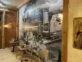 Wnętrze restauracji z muralem przedstawiającym lokomotywę i stoliki.