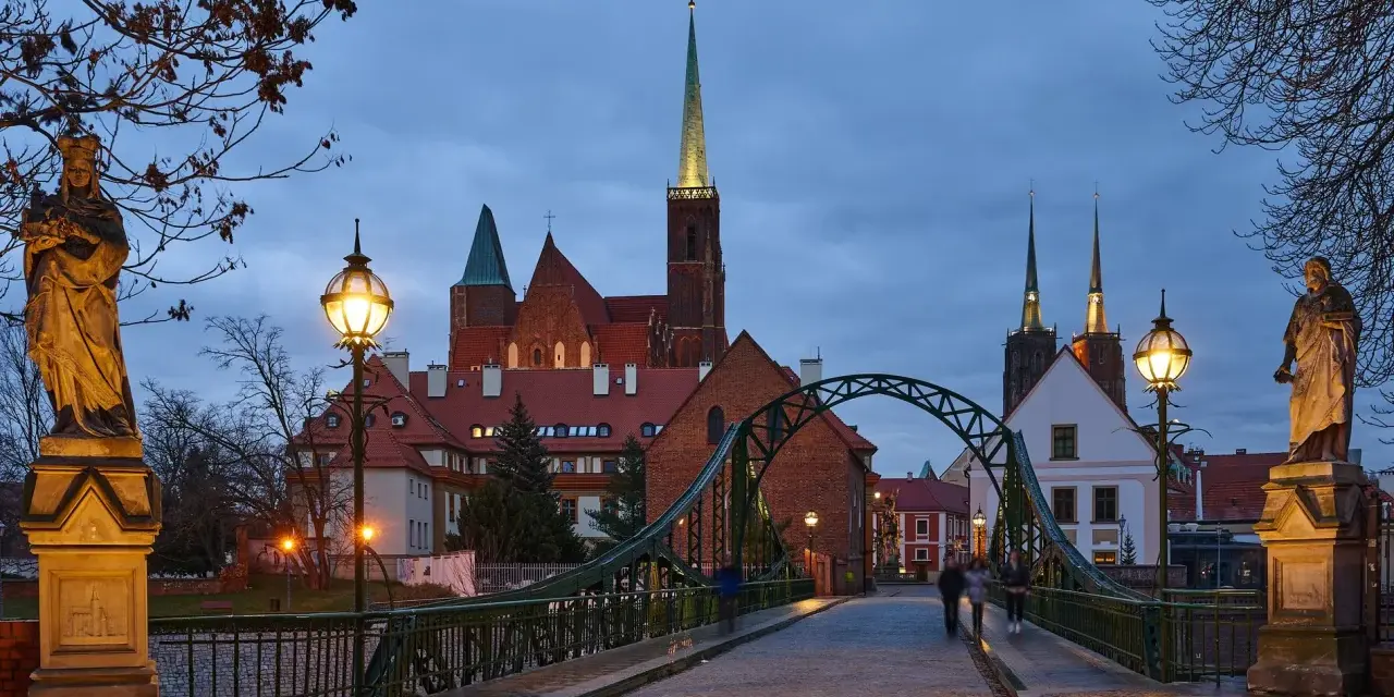 Most wrocławskiej katedry o zmierzchu z widokiem na wieże kościelne i rzeźby.