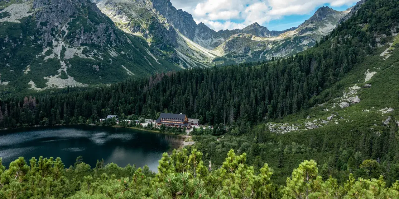Popradzki Staw z hotelem i górami w tle.