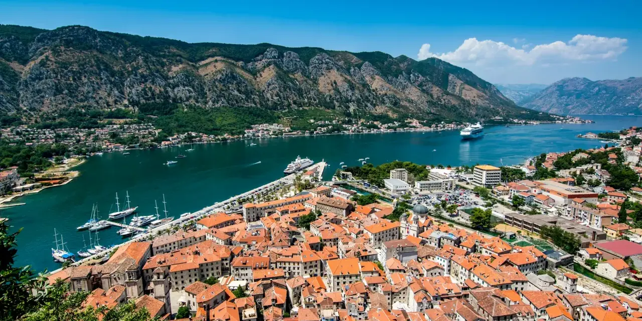 Widok na zabytkowe miasto Kotor w Czarnogórze z zatoką i górami w tle.