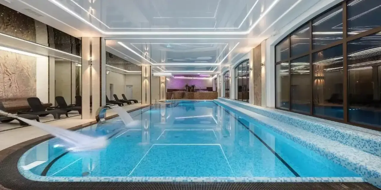 Nowoczesny basen w hotelu spa z wodospadem i leżakami.