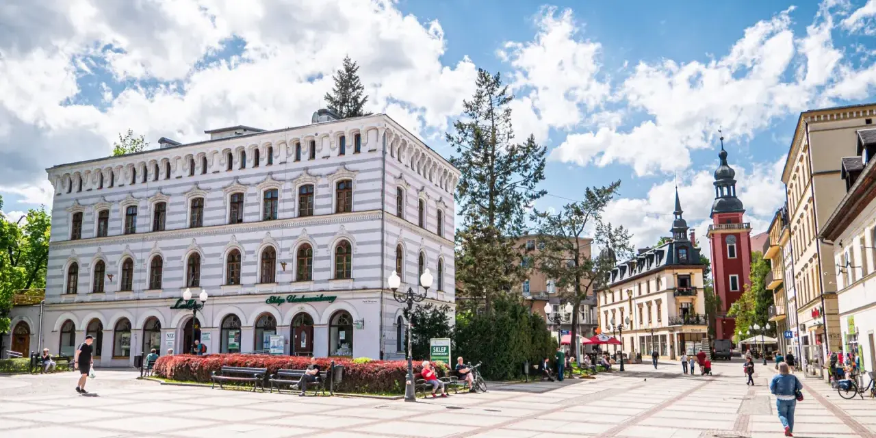 Rynek w Cieplicach Śląskich-Zdroju z zabytkowymi kamienicami i wieżą kościelną.