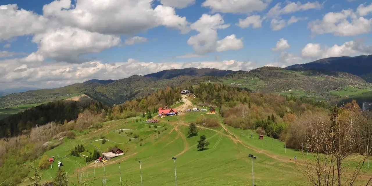 Widok na Palenicę Szczawnica z budynkami, trasami i górami w tle.