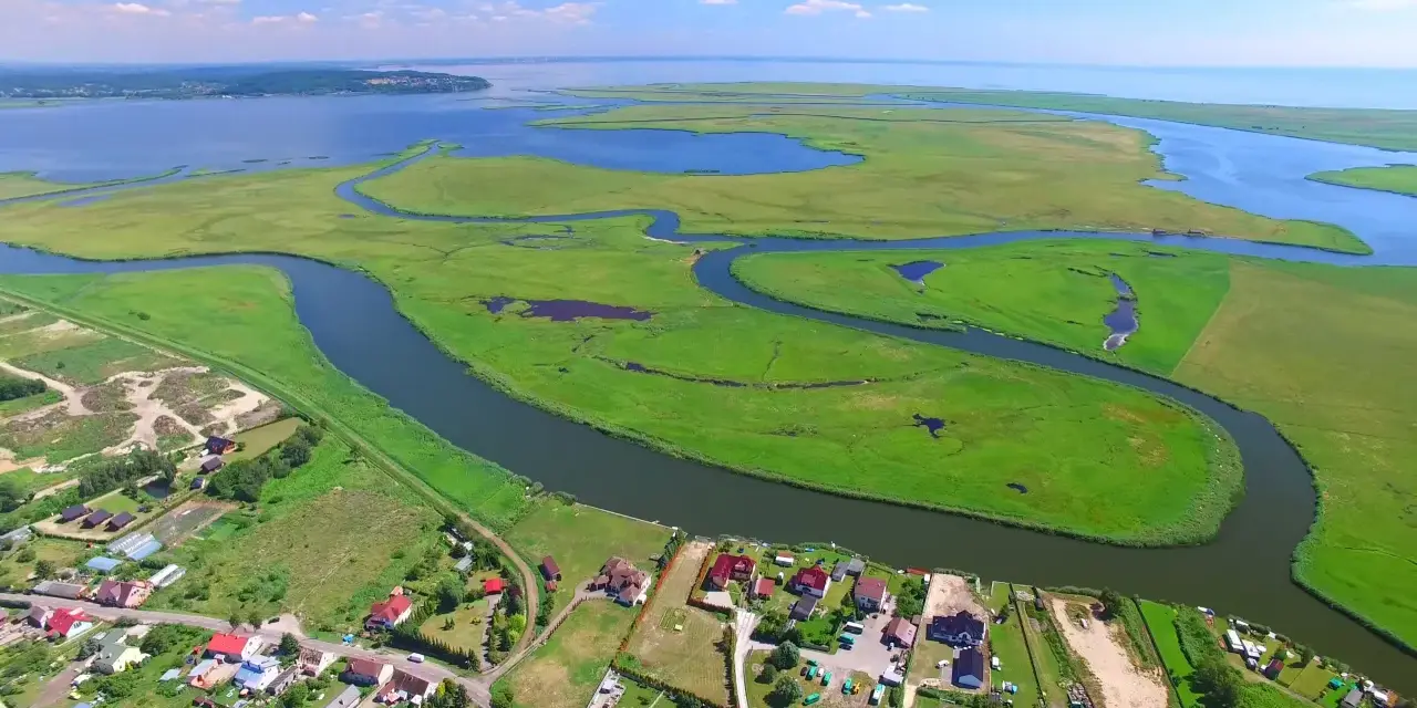 Krajobraz z lotu ptaka: zielone wyspy, meandrujące rzeki i zabudowania nad wodą.