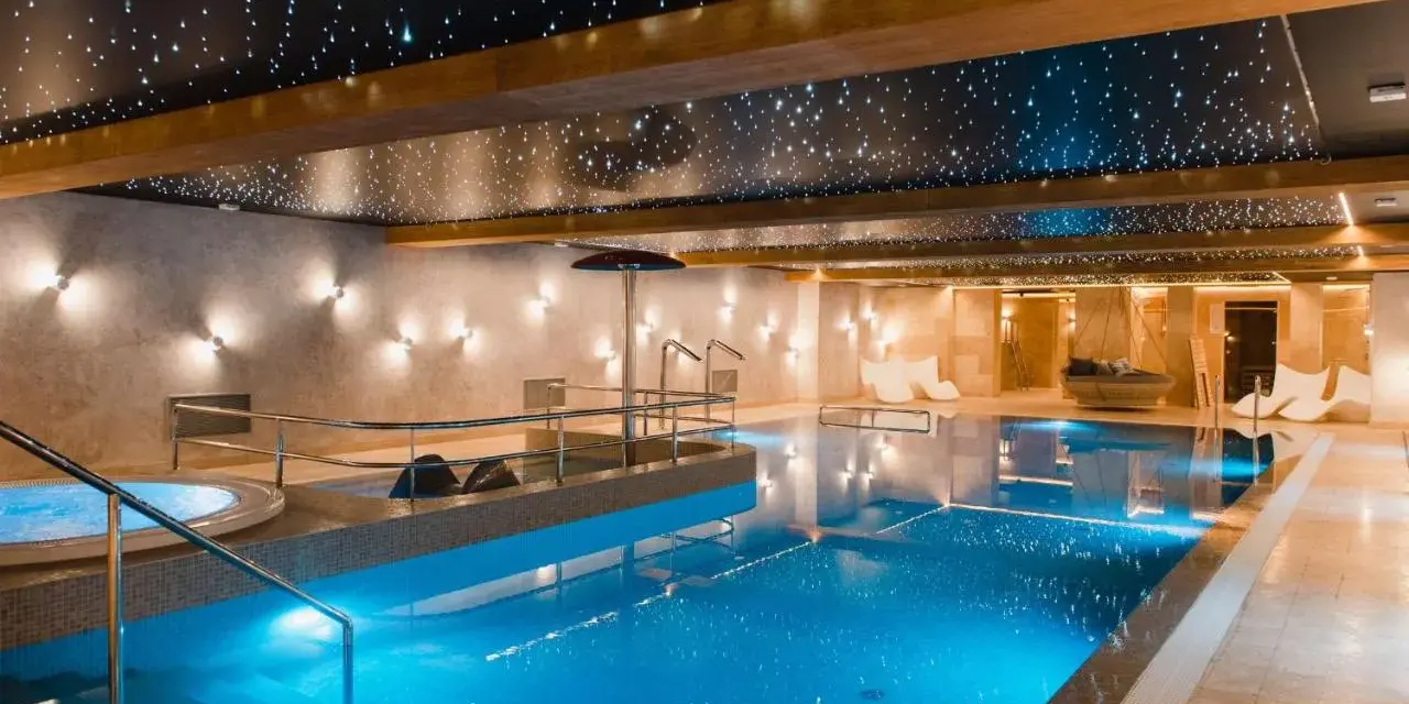 Basen w hotelu SPA z podświetlanym sufitem imitującym gwiazdy i błękitną wodą.