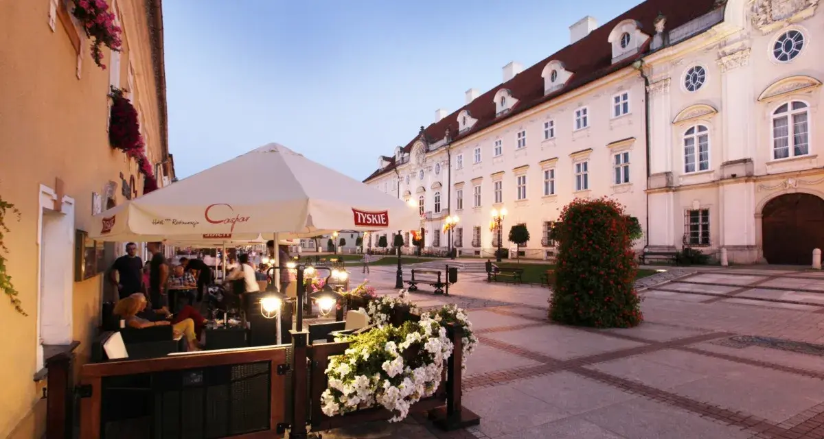 Taras restauracji z parasolami i kwiatami na tle zabytkowej kamienicy w Cieplicach.
