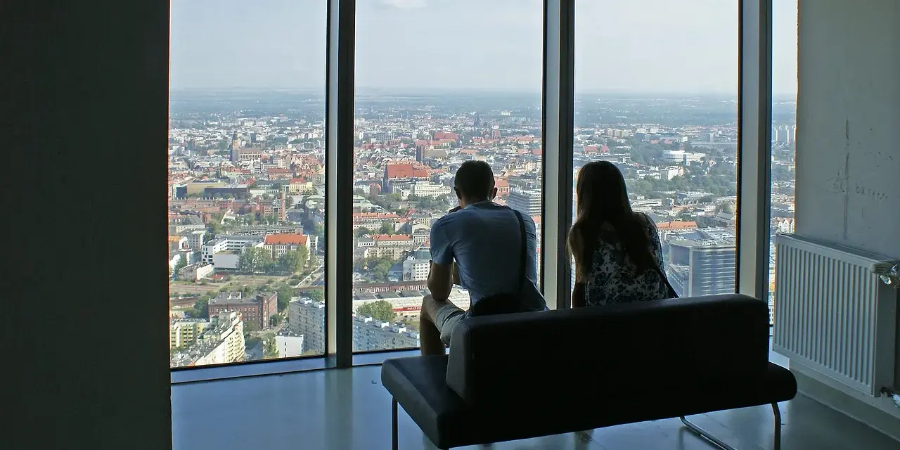 Para siedząca na kanapie, patrząca na panoramę Wrocławia z wysokości.