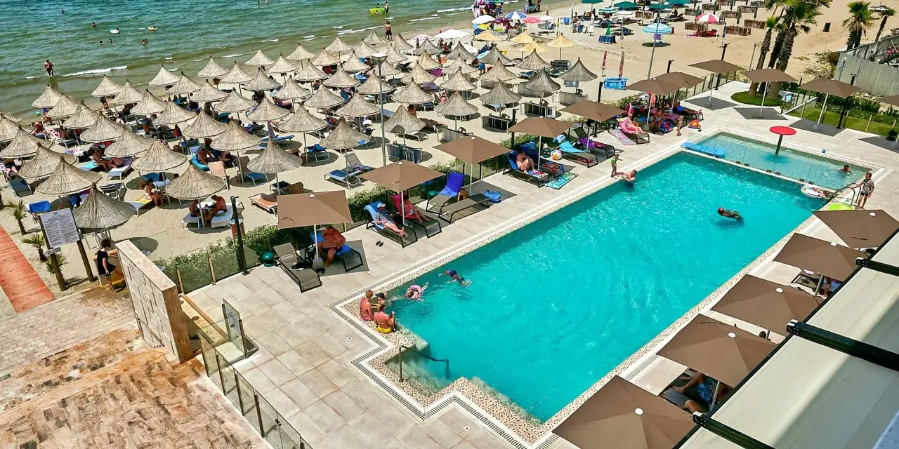 Widok z lotu ptaka na hotelowy basen i plażę z leżakami i parasolami w Durrës, Albania.