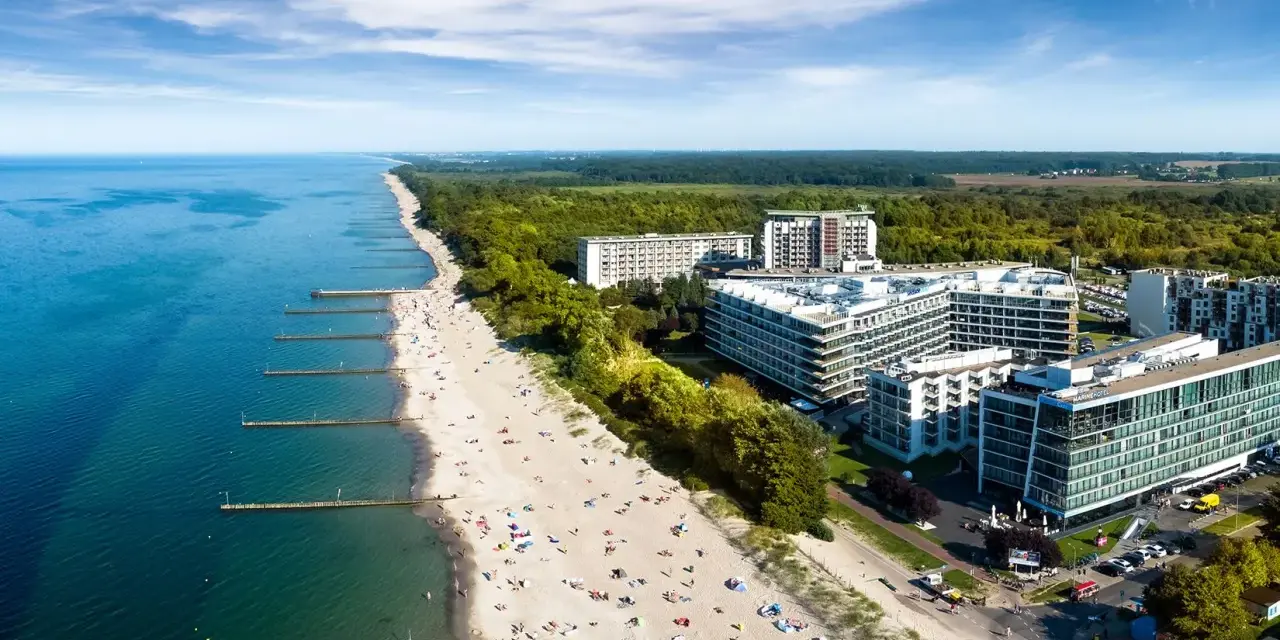 Widok z lotu ptaka na plażę nad Bałtykiem z hotelami i turystami.