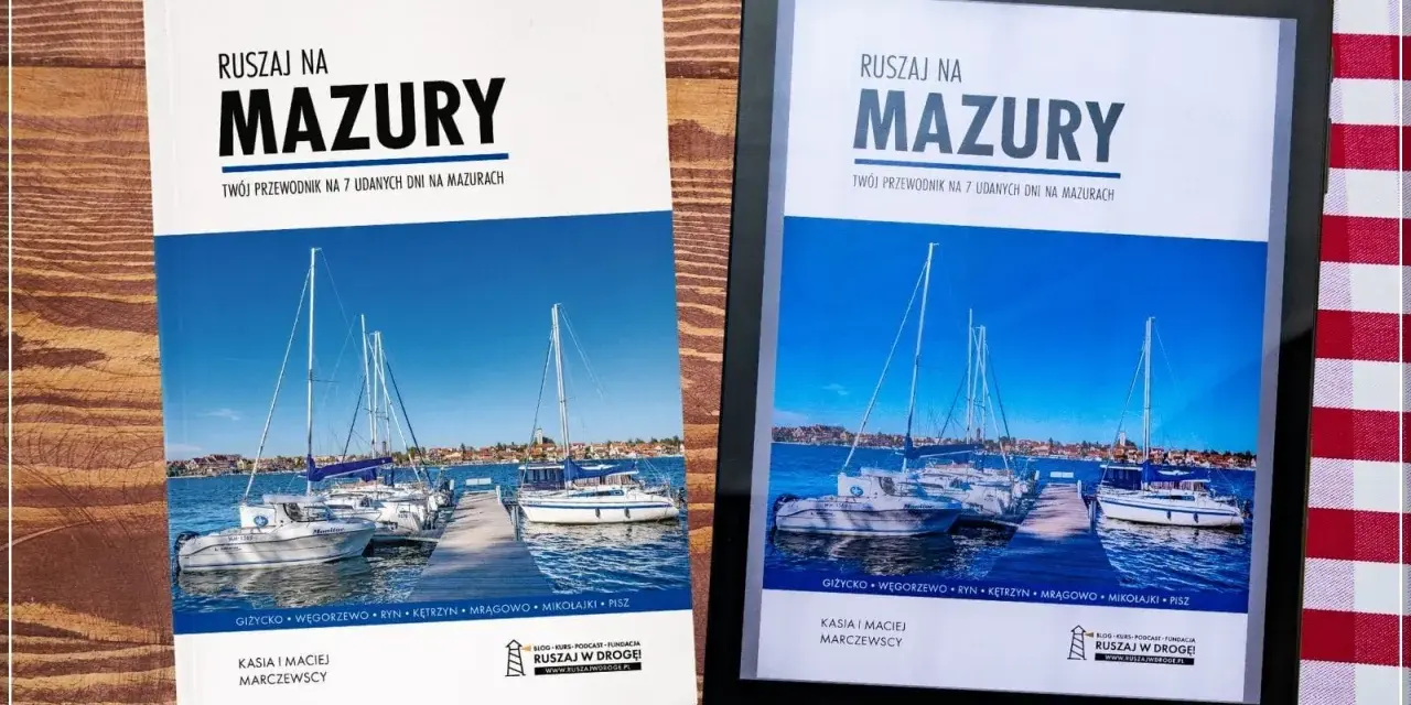 Okładka przewodnika po Mazurach z widokiem na żaglówki przy pomoście.