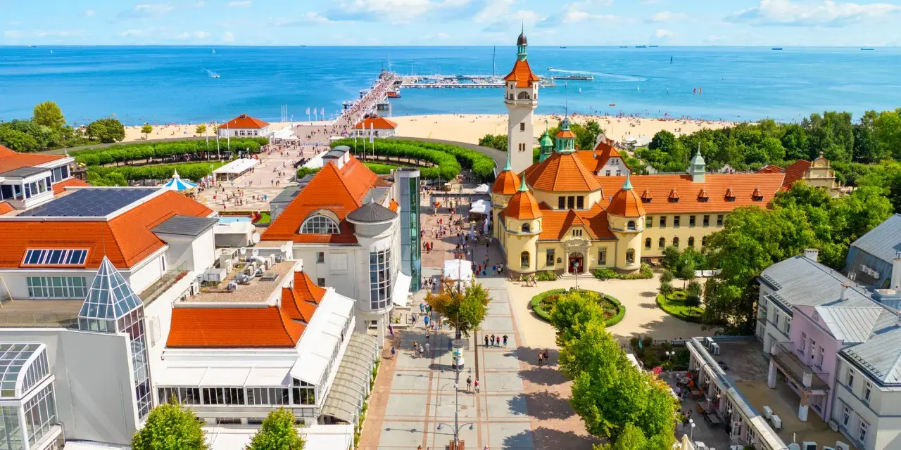 Widok z lotu ptaka na nadmorską miejscowość z plażą, molo i zabytkowymi budynkami.